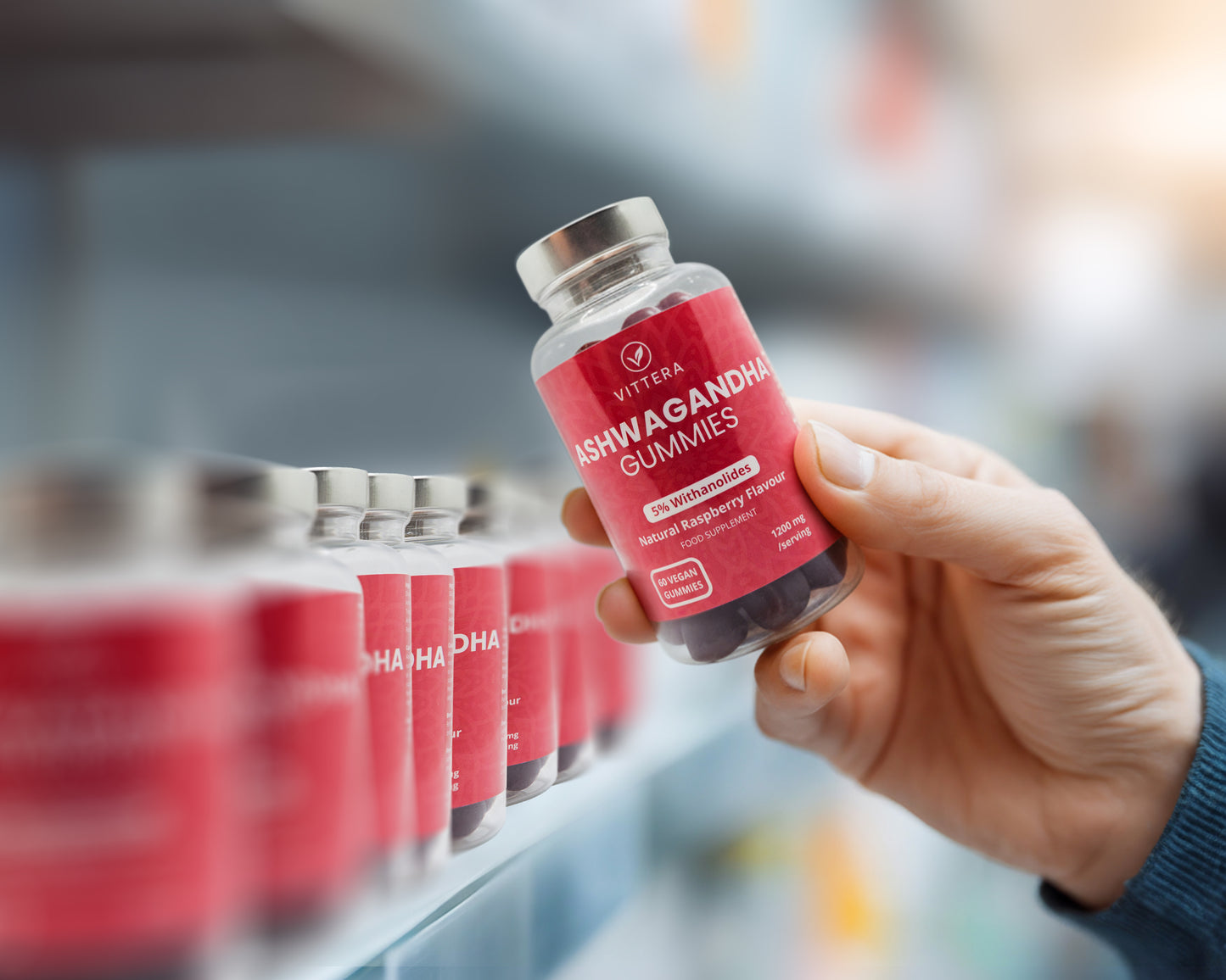 Hand holding a bottle of Vitera Ashwagandha Gummies in a store setting