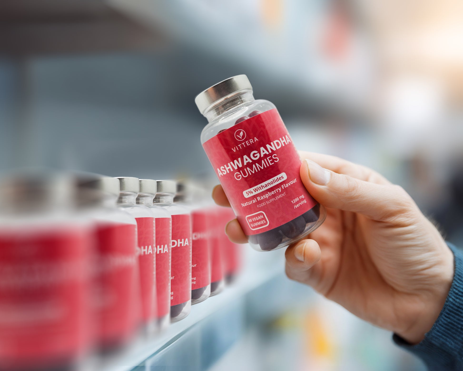 Hand holding a bottle of Vitera Ashwagandha Gummies in a store setting