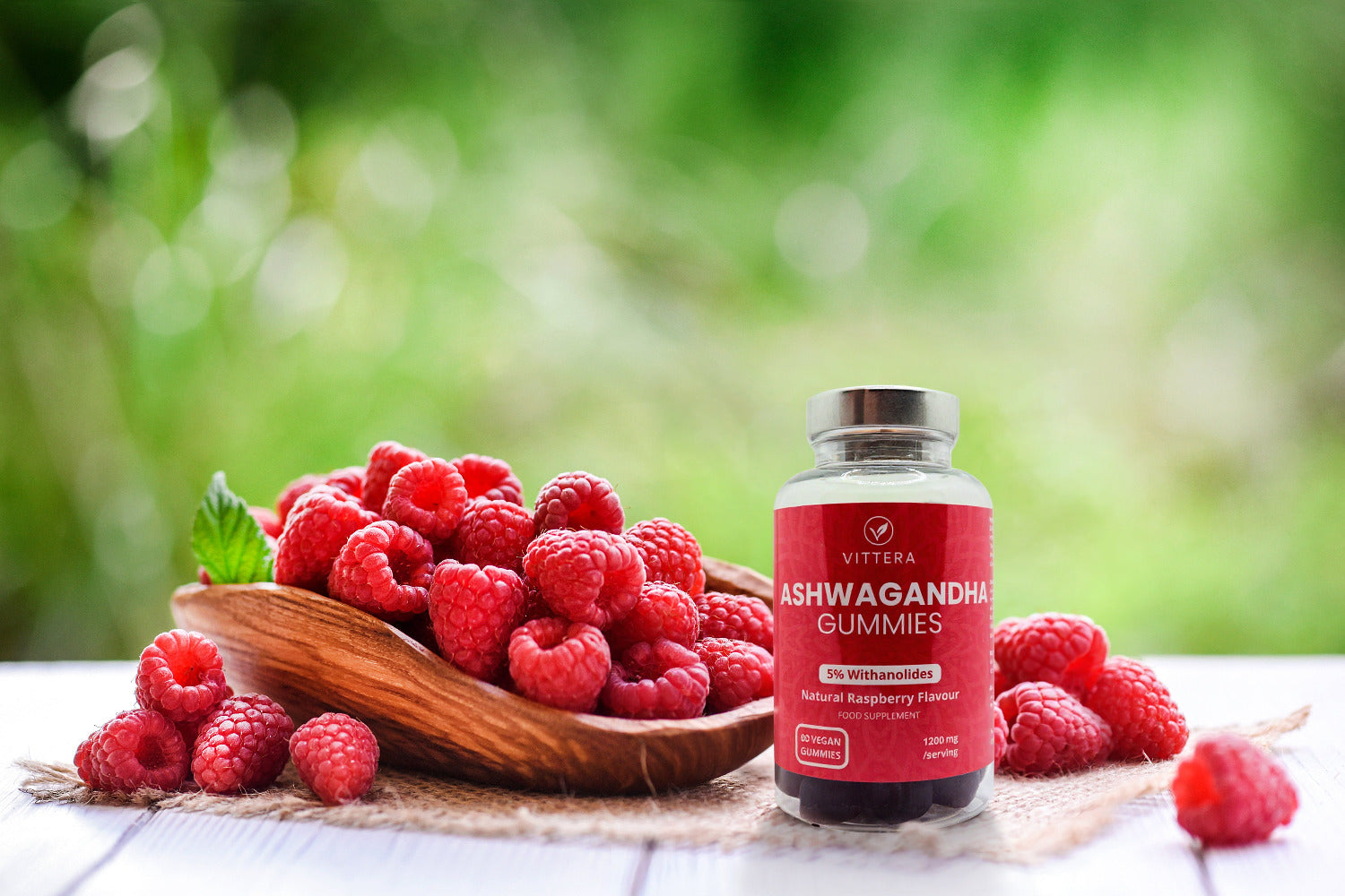 Viterra Ashwagandha gummies bottle with raspberries on a wooden plate outdoors